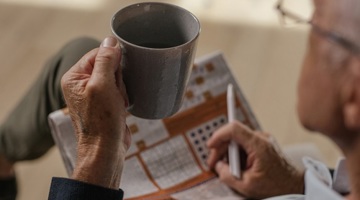 Person holding a cup looking at a puzzle